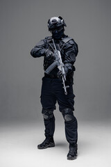 Fototapeta na wymiar Soldier in black uniforms with weapon in studio, man full length photo. Concept Military warrior army tactical force to fight crime in city