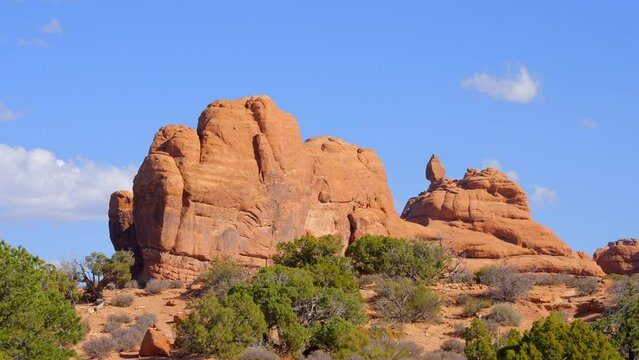 Establishing shot of mountain trail with red rocks background in Double Arch, Arches National Park, Utah, North America. Day time on October 2023. Still camera view. ProRes 422 HQ.