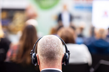 Fototapeta na wymiar Man using translation headphones during international political meeting, business conference, presentation or press conference