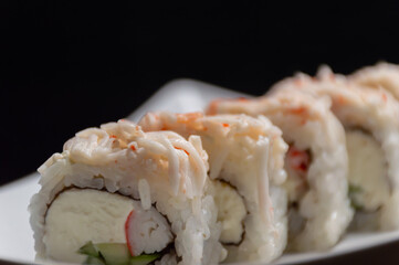 Japanese rolls on a white plate with a black background