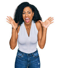 Middle age african american woman wearing casual style with sleeveless shirt celebrating crazy and amazed for success with arms raised and open eyes screaming excited. winner concept