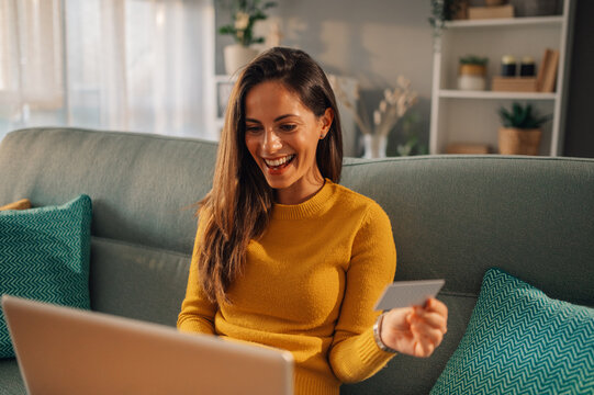 A happy woman is checking on her bank account online on the laptop from home.