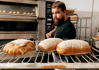 Baker with metallic peel taking out bread from oven