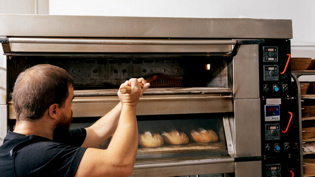 Side view of man cleaning appliance in bakery
