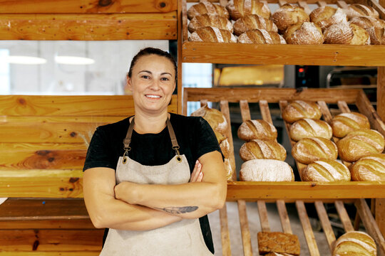 Happy saleswoman standing by bread in bakery shop