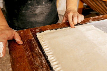 Chef's hand pressing dough edges in kitchen