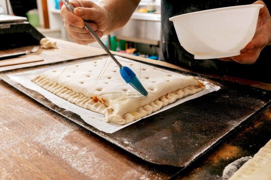 Male baker smearing pastry before baking - Powered by Adobe