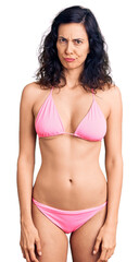 Young beautiful hispanic woman wearing bikini skeptic and nervous, frowning upset because of problem. negative person.