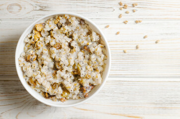 Kutya, a traditional Ukrainian Christmas dish made of wheat groats on the table for Christmas or the old New Year. Boiled porridge with walnuts, raisins, poppy seeds and honey in a white bowl.