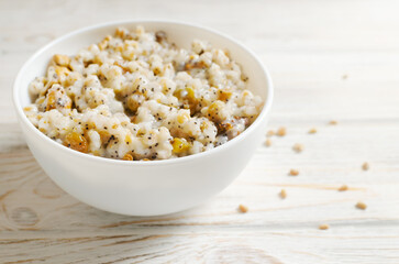 Kutya, a traditional Ukrainian Christmas dish made of wheat groats on the table for Christmas or the old New Year. Boiled porridge with walnuts, raisins, poppy seeds and honey in a white bowl.