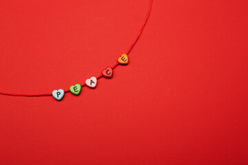 Colored heart shaped beads with letters on them strung on a red rustic rope making 