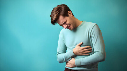 Young man holding his stomach with his hands, experiencing pain in his abdominal region, medical and health care problem concept, adult person belly inflammation, gastritis symptoms 