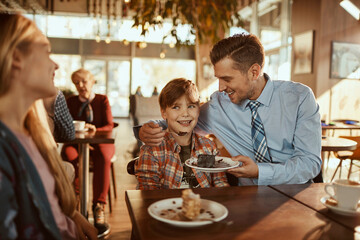 Father feeding son cake at the cafe