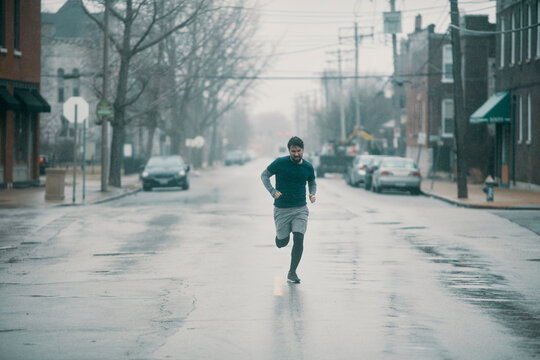 Young man running during bad weather in the city