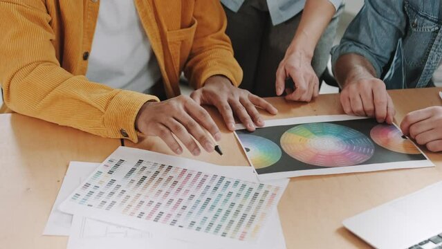 hands of designers at a workplace with color palettes on paper
