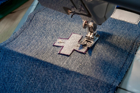 Sewing machine stitching a patch on denim fabric