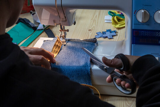 Tailor's hands sewing denim on a sewing machine