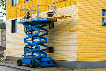 Using a scissor lift in facade cladding works after spraying the facade with thermal insulation foam - obrazy, fototapety, plakaty