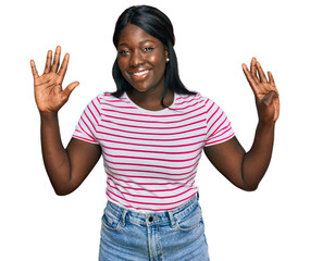 African young woman wearing casual striped t shirt showing and pointing up with fingers number nine...
