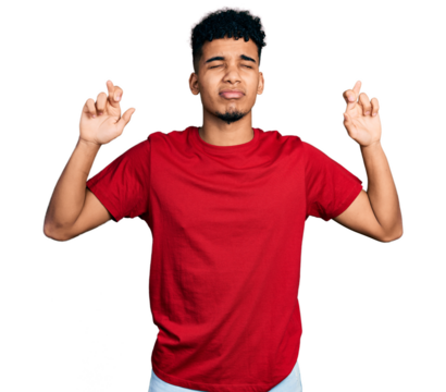 Young african american man wearing casual red t shirt gesturing finger crossed smiling with hope and eyes closed. luck and superstitious concept.