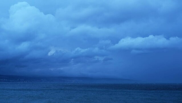 Fast motion fluffy tropical storm clouds moving above the sea on a windy morning. Magnificent nature landscape in blue hour. Relaxing or meditative, continuously changing cloudscapes for background.