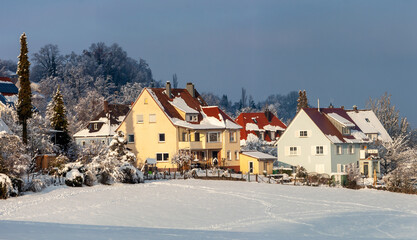 Beautiful winter in a European village - view of a snow-covered field against the backdrop of country houses