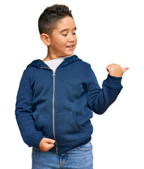 Little boy hispanic kid wearing casual sporty jacket smiling with happy face looking and pointing to the side with thumb up.