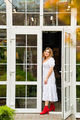 an attractive woman in a white summer dress on the threshold of a country house