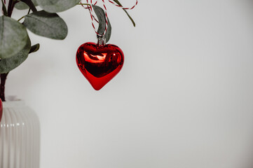 minimalistic christmas background with red heart ornament on white background