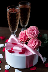 Beautiful surprise greeting for saint Valentine's or Women's Day, birthday or Anniversary for beloved. Fresh pink roses, gift box with sweets. Dark background. Holiday atmosphere