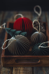 Cozy atmospheric photo, home festive atmosphere. Collection of old fashioned christmas new year foldable honeycomb toys, craft holiday decoration in vintage wooden box. Magic lights on background