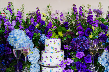 Table with sweets and cakes decorated with bouquets of purple flowers. 