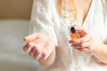 Beautiful young woman using perfume at home