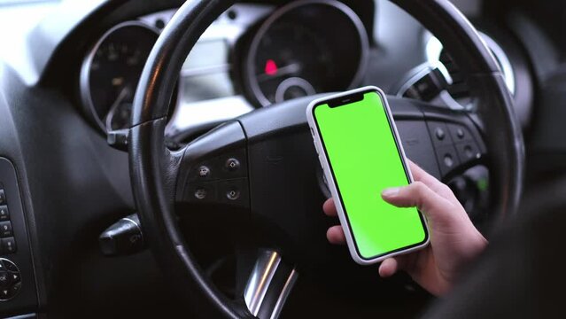 Close up of a man's hand holding a mobile telephone with a vertical green screen in car chroma key smartphone technology cell phone street touch message display hand.