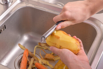 Female hands peeling a potato in sink in the kitchen. Vegetables, vegetarian, preparation for cooking, healthy food, food lifestyle, close up, food lifestyle