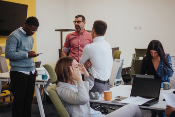 Young, female employee struggling severe headaches caused of migraine during working hours with her coworkers at modern office.