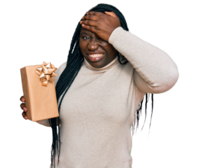 Young black woman with braids holding gift stressed and frustrated with hand on head, surprised and angry face
