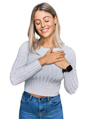 Beautiful blonde woman wearing casual clothes smiling with hands on chest with closed eyes and grateful gesture on face. health concept.