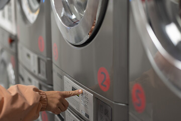  Female hand visible pushing a button on the machine at a laundromat. Automatically controlled...