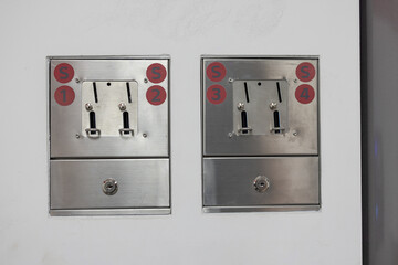 Vending machines at laundromat. Visible slots for tokens to wash your laundry, frontal view.