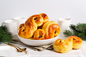 Homemade  swedish St Lucia saffron buns. on a white table. Also called  lussekatt or lussebulle, Cornish tea treat bun or revel bun, with  raisins. Christmas decoration.