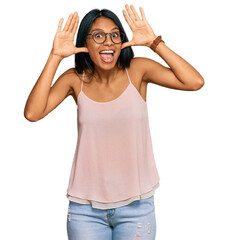 Obraz na płótnie Canvas Young african american woman wearing casual clothes and glasses smiling cheerful playing peek a boo with hands showing face. surprised and exited