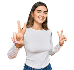 Young hispanic woman wearing casual clothes smiling looking to the camera showing fingers doing...