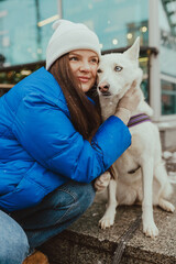 A beautiful young girl hugging her white dog in winter, Festive New Year's mood, happy woman with a dog at Christmas time