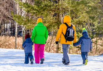 Fototapeta na wymiar A married couple with children walks through the winter forest 