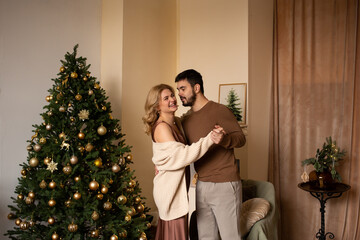 Couple at home enjoying their time together standing next to Christmas tree