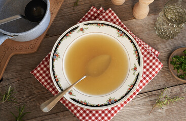 Chicken soup or broth in a plate, top view