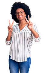 Young african american woman wearing casual clothes and glasses smiling looking to the camera showing fingers doing victory sign. number two.