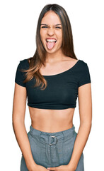 Young brunette woman wearing casual clothes sticking tongue out happy with funny expression. emotion concept.