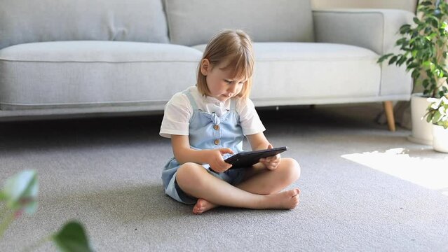 A preschool girl uses a digital device. Children's educational apps for tablets